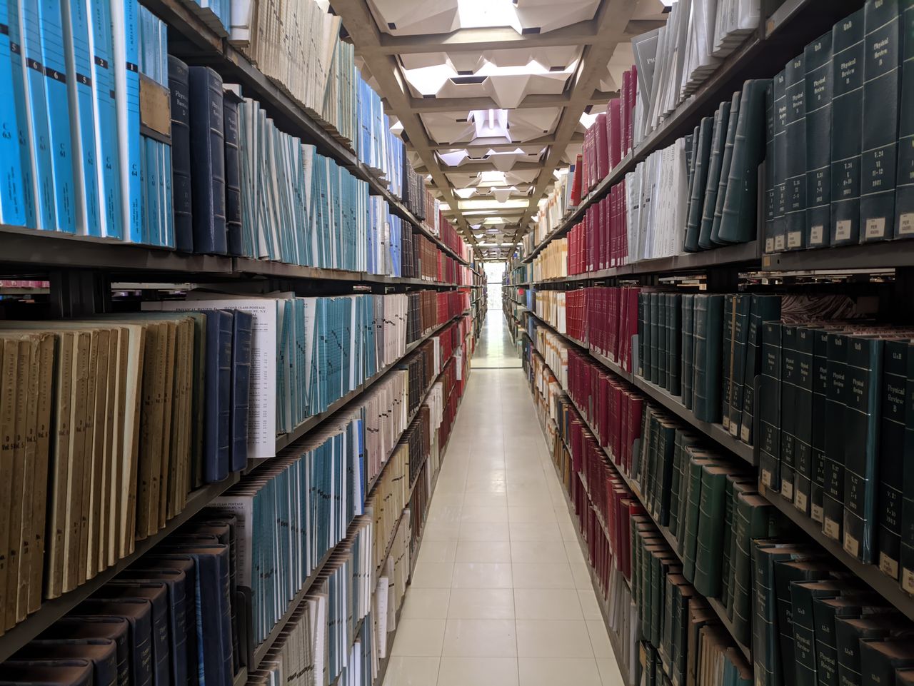 Services Perspective view of an extensive library aisle filled with colorful bookshelves.
